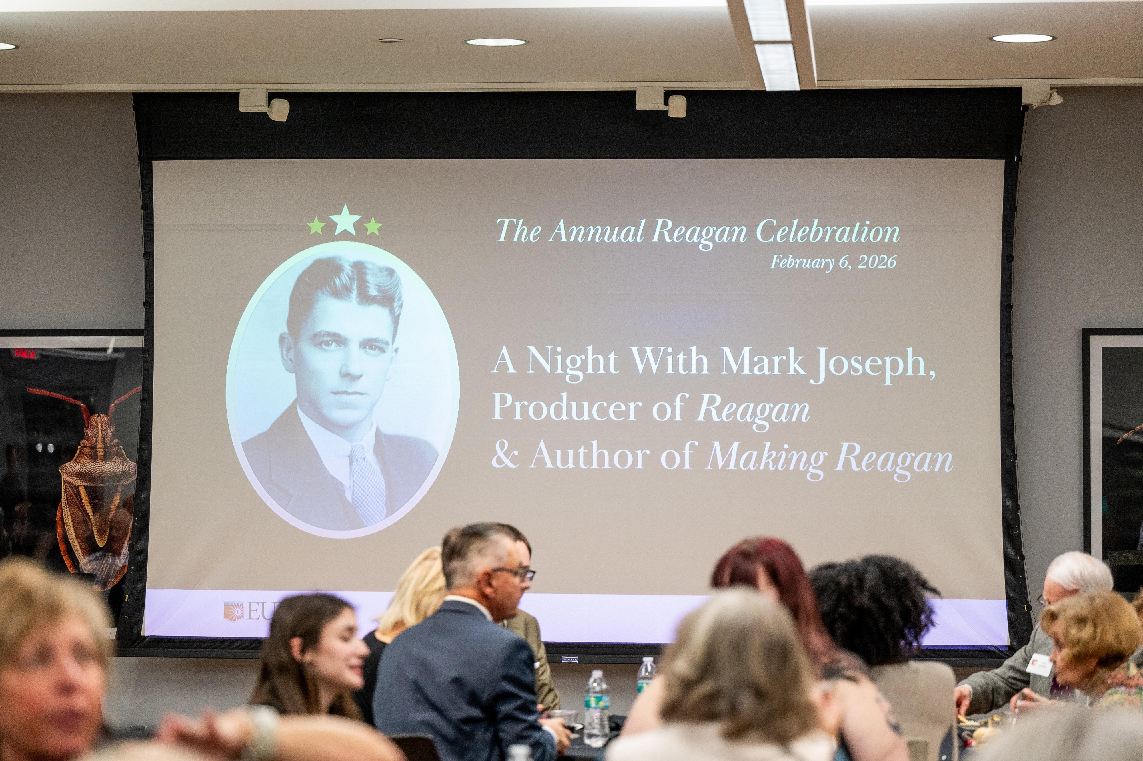 An audience watching a presentation projected on screen at the Reagan Celebration
